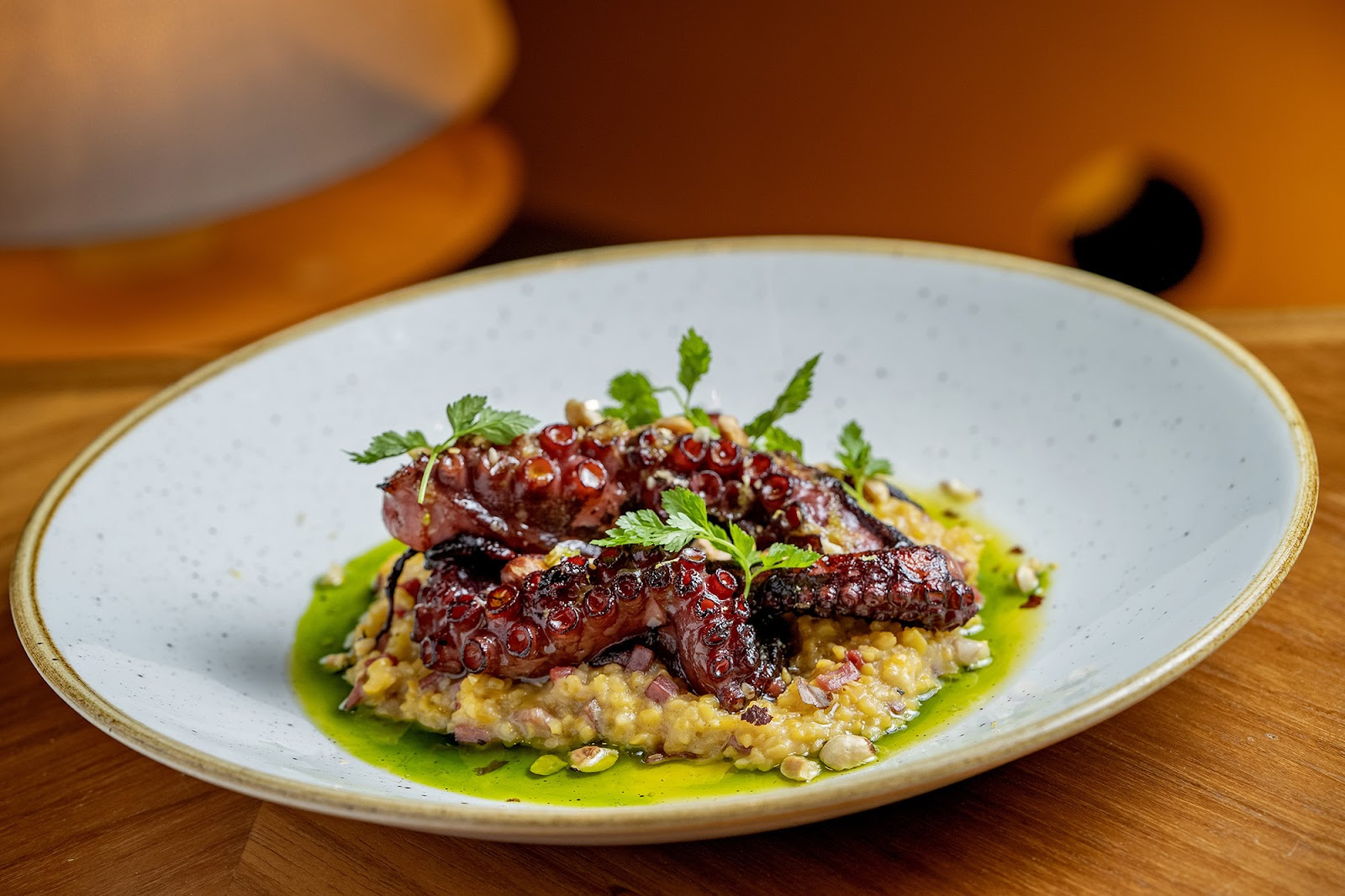 Polvo grelhado com canjiquinha de milho, linguiça de Bragança, guanciale e gremolata de avelã